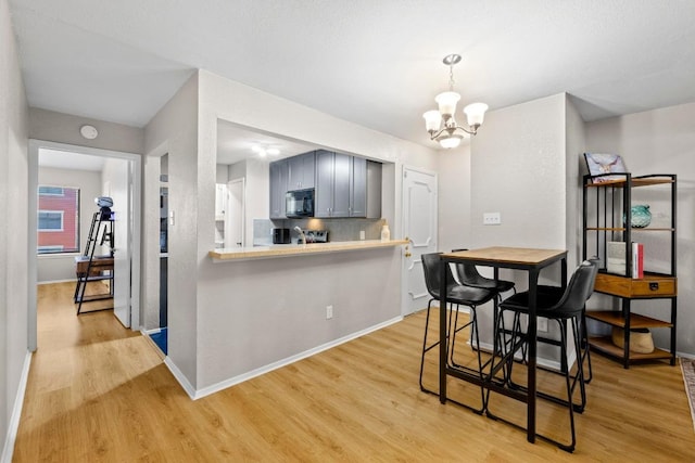 806 W 24th St Unit 302, Austin, TX 78705 - kitchen with black microwave, light wood finished floors, a chandelier, light countertops, and baseboards