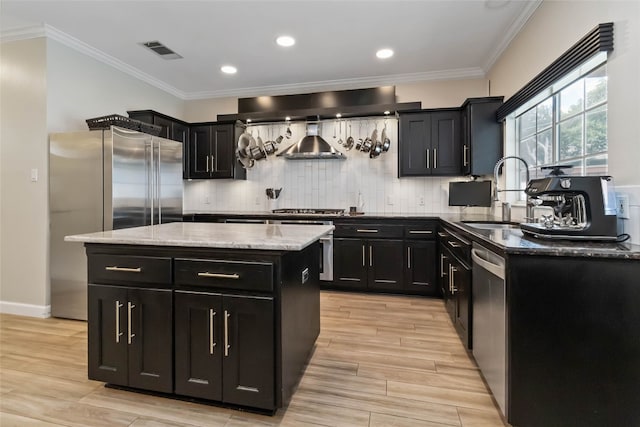 3836 NE Newland Ct, Round Rock, TX 78681 - kitchen featuring dark cabinetry, wall chimney exhaust hood, decorative backsplash, a center island, and crown molding