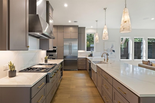 4600 Parkdale Pl Unit 1, Austin, TX 78745 - kitchen featuring stainless steel appliances, wall chimney exhaust hood, gray cabinets, recessed lighting, and light wood-style flooring