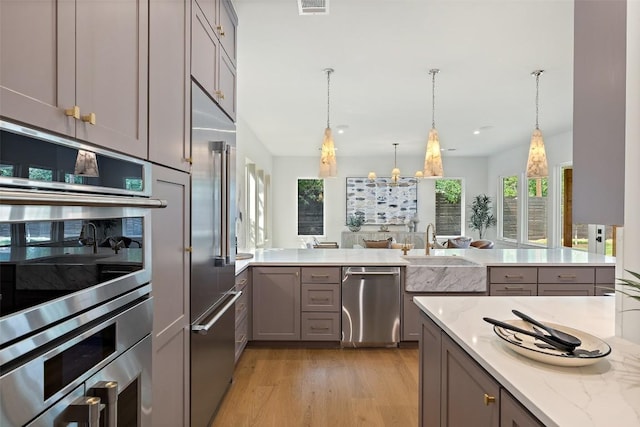 4600 Parkdale Pl Unit 1, Austin, TX 78745 - kitchen featuring stainless steel appliances, gray cabinetry, light stone countertops, light wood-style floors, and a peninsula