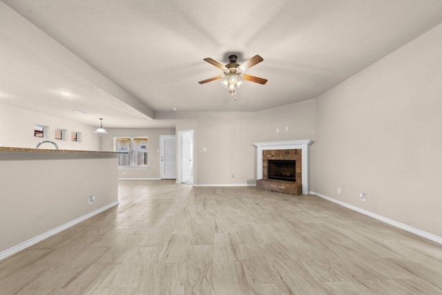 4201 Colonel Dr, Killeen, TX 76549 - unfurnished living room featuring a ceiling fan, a fireplace, a textured ceiling, and light wood-style flooring