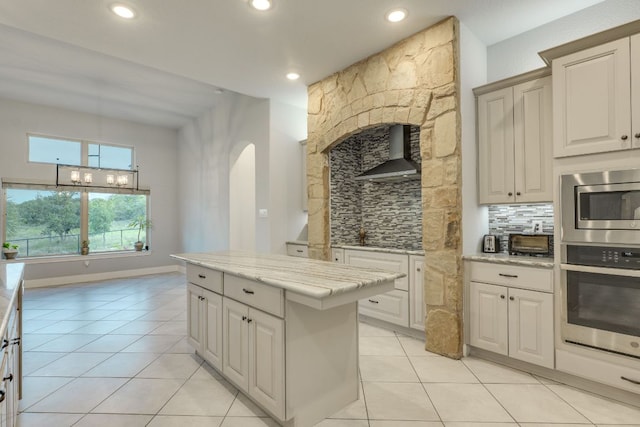 346 Blackbird Dr, Spring Branch, TX 78070 - kitchen with stainless steel appliances, wall chimney range hood, tasteful backsplash, light tile patterned floors, and arched walkways