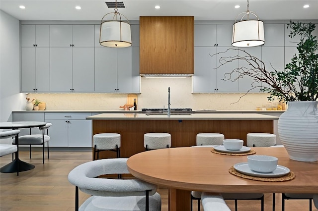 2635 Barton Hills Dr, Austin, TX 78704 - kitchen featuring recessed lighting, decorative backsplash, decorative light fixtures, a kitchen island with sink, and dark wood-type flooring