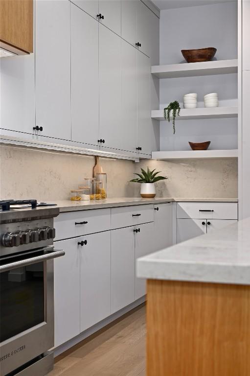 2635 Barton Hills Dr, Austin, TX 78704 - kitchen with high end range, open shelves, decorative backsplash, and white cabinetry