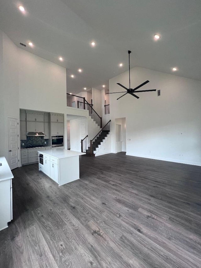 1340 Robin Trl, Round Rock, TX 78681 - unfurnished living room featuring high vaulted ceiling, dark wood finished floors, ceiling fan, stairs, and recessed lighting