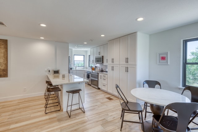 3305 Close Call, Horseshoe Bay, TX 78657 - kitchen with appliances with stainless steel finishes, a peninsula, a breakfast bar, recessed lighting, and light wood-style floors