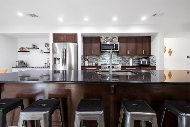 12519 Split Rail Pkwy, Austin, TX 78750 - kitchen with appliances with stainless steel finishes, tasteful backsplash, open shelves, a breakfast bar area, and dark stone counters