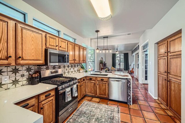 8660 Ephraim Rd, Austin, TX 78717 - kitchen with stainless steel appliances, a sink, a peninsula, tasteful backsplash, and brown cabinetry