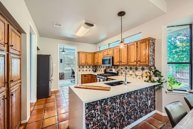 8660 Ephraim Rd, Austin, TX 78717 - kitchen featuring stainless steel appliances, a sink, brown cabinetry, tasteful backsplash, and a peninsula