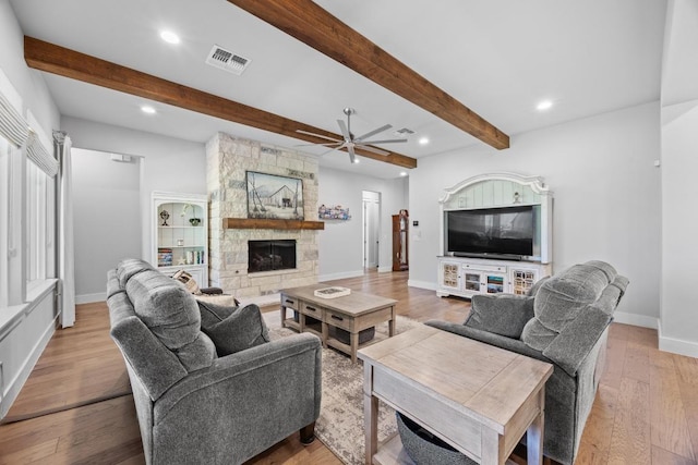2208 Quarry Loop, Leander, TX 78641 - living area with a ceiling fan, recessed lighting, beam ceiling, wood finished floors, and a stone fireplace
