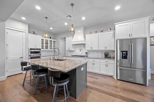 2208 Quarry Loop, Leander, TX 78641 - kitchen with stainless steel appliances, custom range hood, recessed lighting, light wood-style floors, and white cabinets