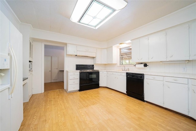 2208 US Highway 96 S, Center, TX 75935 - kitchen with black appliances, light wood-style flooring, white cabinets, a skylight, and tasteful backsplash