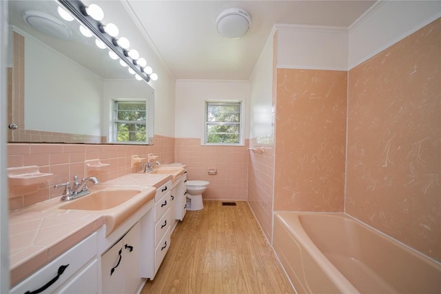 2208 US Highway 96 S, Center, TX 75935 - bathroom featuring wood finished floors, tile walls, double vanity, toilet, and wainscoting