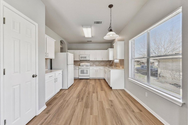 164 Ashwood S, Kyle, TX 78640 - kitchen with white appliances, a sink, light wood-type flooring, light countertops, and decorative backsplash