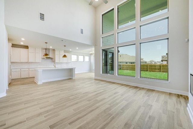 216 Ranchland Pass, Liberty Hill, TX 78642 - unfurnished living room featuring light wood-type flooring, a high ceiling, and a ceiling fan