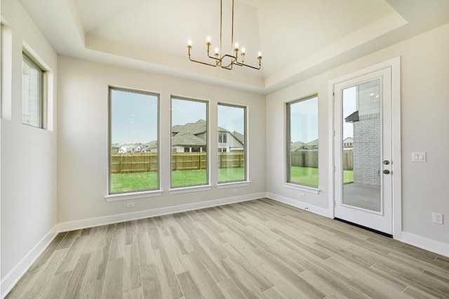 216 Ranchland Pass, Liberty Hill, TX 78642 - unfurnished dining area featuring a raised ceiling, a chandelier, and light wood-style flooring