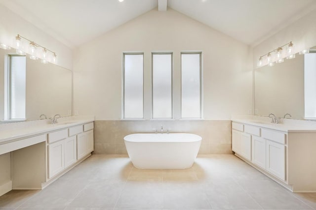 216 Ranchland Pass, Liberty Hill, TX 78642 - full bathroom featuring two vanities, tile walls, tile patterned floors, a freestanding bath, and vaulted ceiling