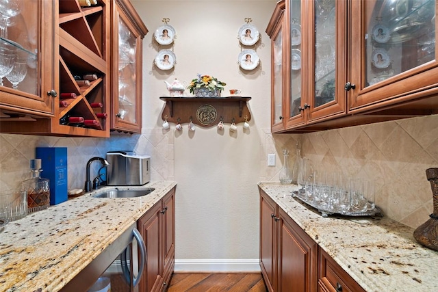 407 Bella Montagna Cir, Austin, TX 78734 - kitchen featuring baseboards, wood finished floors, light stone counters, a sink, and brown cabinetry