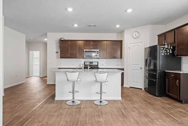 936 Vogel Dr, Georgetown, TX 78626 - kitchen featuring stainless steel appliances, light wood-type flooring, tasteful backsplash, dark brown cabinets, and recessed lighting