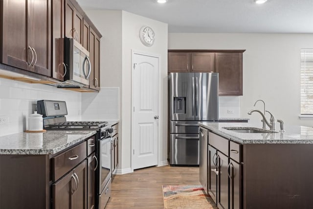 936 Vogel Dr, Georgetown, TX 78626 - kitchen with stainless steel appliances, wood finished floors, dark brown cabinetry, light stone countertops, and backsplash
