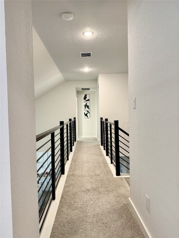 422 Billowing Way, Kyle, TX 78640 - corridor featuring an upstairs landing, a textured wall, carpet floors, a textured ceiling, and baseboards