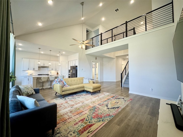 422 Billowing Way, Kyle, TX 78640 - living area with stairway, dark wood-style flooring, ceiling fan, recessed lighting, and high vaulted ceiling