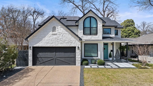 1102 Kinney Ave, Austin, TX 78704 - french country style house with driveway, solar panels, stone siding, a front lawn, and roof with shingles