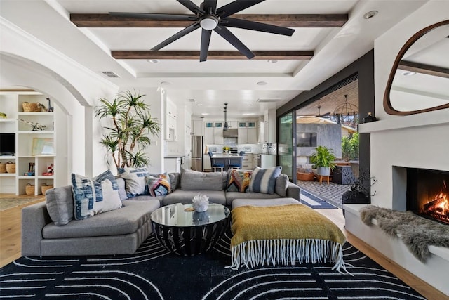 1102 Kinney Ave, Austin, TX 78704 - living area featuring ceiling fan, wood finished floors, a lit fireplace, and beamed ceiling
