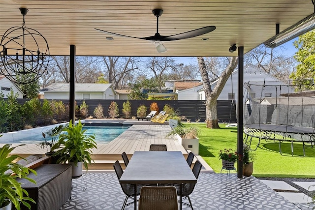 1102 Kinney Ave, Austin, TX 78704 - fenced backyard featuring a trampoline, a patio, a ceiling fan, and outdoor dining space