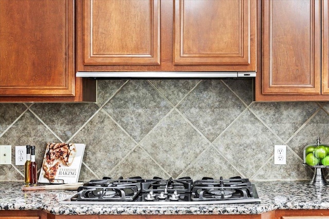 295 Desert Wilow Way, Austin, TX 78737 - kitchen with stainless steel gas stovetop, tasteful backsplash, brown cabinetry, and light stone countertops