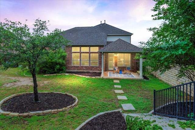295 Desert Wilow Way, Austin, TX 78737 - back of house at dusk featuring a shingled roof, a patio area, and brick siding