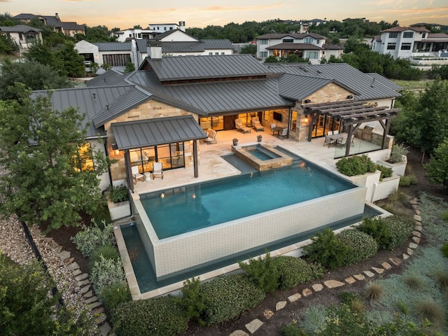 12625 Maidenhair Ln Unit 32, Austin, TX 78738 - back of property at dusk with a standing seam roof, a patio area, a pool with connected hot tub, and metal roof