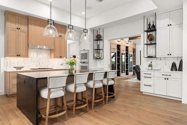 12625 Maidenhair Ln Unit 32, Austin, TX 78738 - kitchen featuring white gas cooktop, light wood-style floors, tasteful backsplash, a kitchen breakfast bar, and recessed lighting