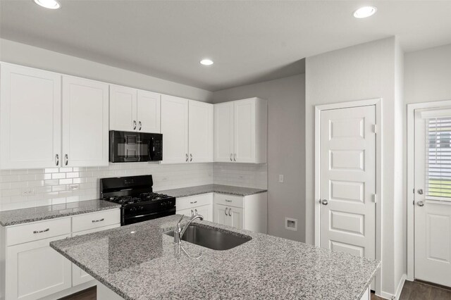 246 Barley Ln, Elgin, TX 78621 - kitchen featuring black appliances, an island with sink, light stone countertops, white cabinets, and tasteful backsplash
