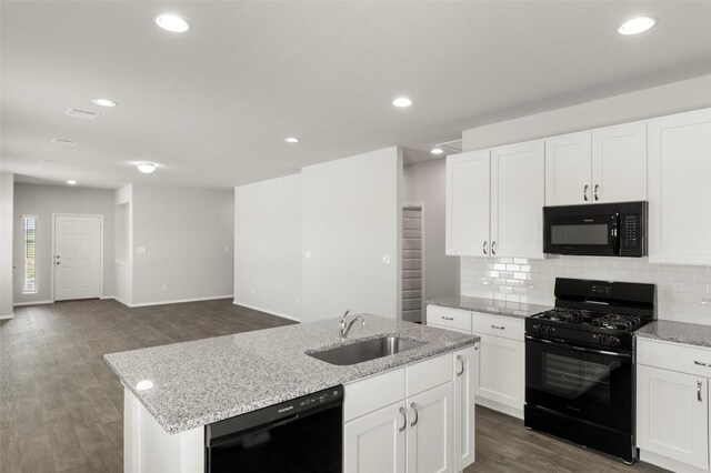 246 Barley Ln, Elgin, TX 78621 - kitchen with black appliances, a center island with sink, backsplash, dark wood-type flooring, and light stone counters