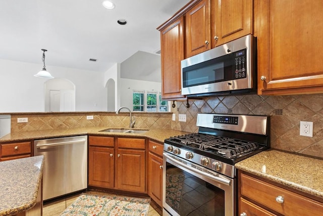 221 Mcgarity St, Kyle, TX 78640 - kitchen featuring appliances with stainless steel finishes, a sink, brown cabinets, light stone counters, and recessed lighting