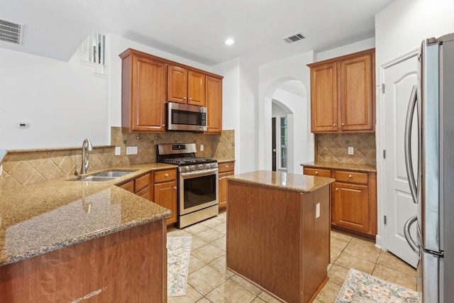 221 Mcgarity St, Kyle, TX 78640 - kitchen featuring appliances with stainless steel finishes, a sink, light stone countertops, arched walkways, and recessed lighting