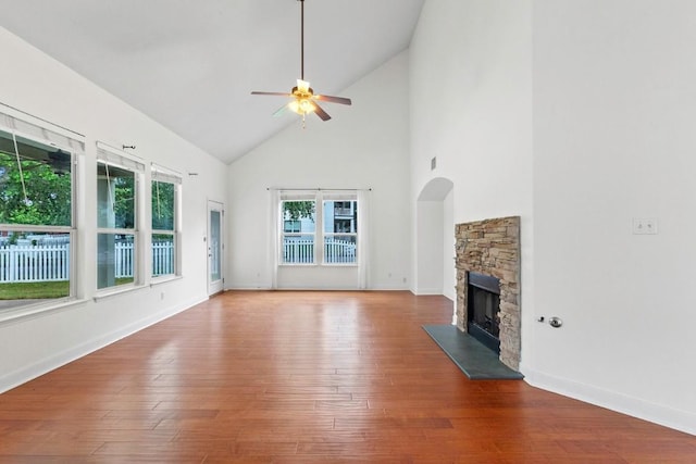 221 Mcgarity St, Kyle, TX 78640 - unfurnished living room with high vaulted ceiling, ceiling fan, a stone fireplace, wood finished floors, and baseboards