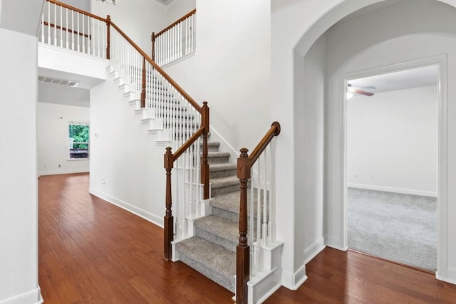 221 Mcgarity St, Kyle, TX 78640 - stairway with hardwood / wood-style floors, arched walkways, a ceiling fan, baseboards, and a towering ceiling