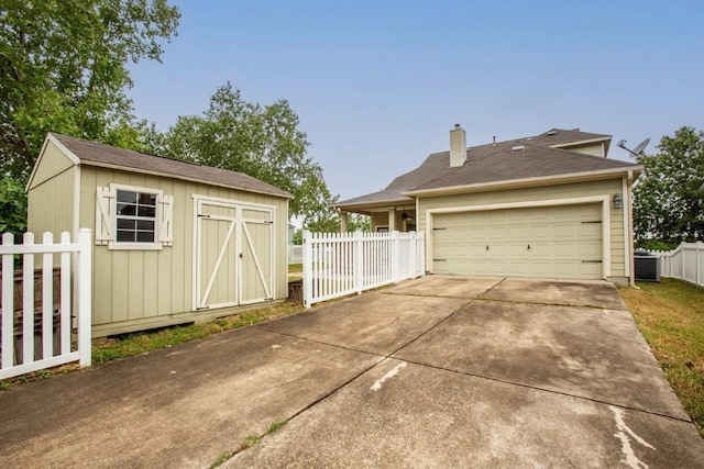 221 Mcgarity St, Kyle, TX 78640 - garage featuring a storage shed, driveway, and cooling unit