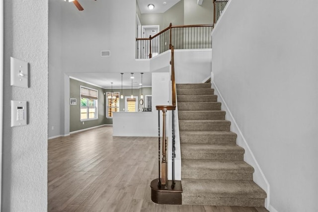 1913 Gabrielles Way, Manchaca, TX 78652 - staircase featuring a towering ceiling, wood finished floors, baseboards, ceiling fan, and a chandelier