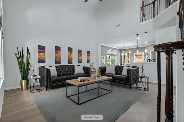 1913 Gabrielles Way, Manchaca, TX 78652 - living area featuring wood finished floors, baseboards, a high ceiling, ornamental molding, and a chandelier