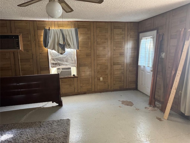 137 N Kowald Ln, New Braunfels, TX 78130 - unfurnished bedroom with a textured ceiling, wood walls, cooling unit, concrete floors, and a ceiling fan