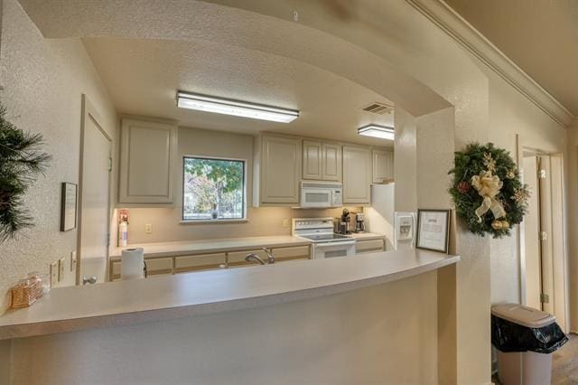 104 Mason Ct, Horseshoe Bay, TX 78657 - kitchen featuring white appliances, a peninsula, light countertops, a textured wall, and a textured ceiling