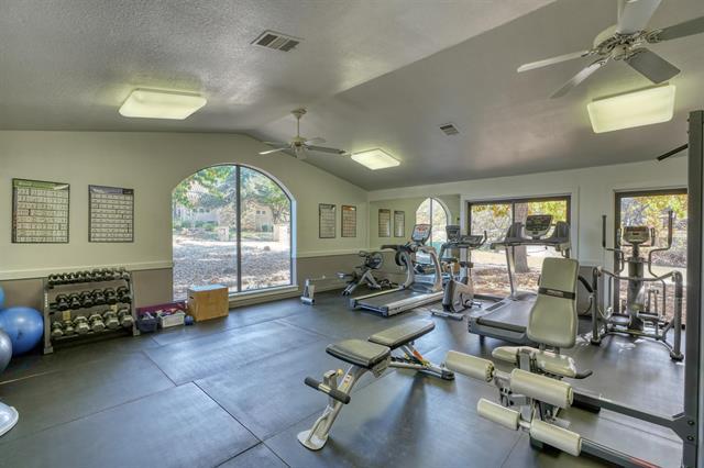 104 Mason Ct, Horseshoe Bay, TX 78657 - exercise room featuring ceiling fan, vaulted ceiling, and a textured ceiling