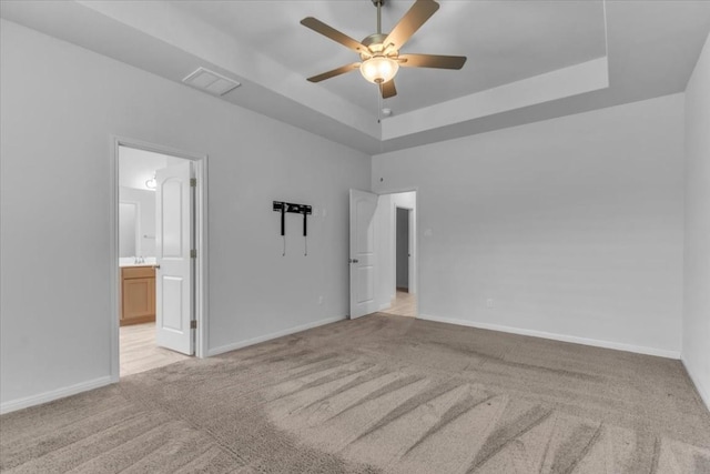 308 Castlefields St, Hutto, TX 78634 - unfurnished bedroom with light carpet, a tray ceiling, ensuite bathroom, and ceiling fan