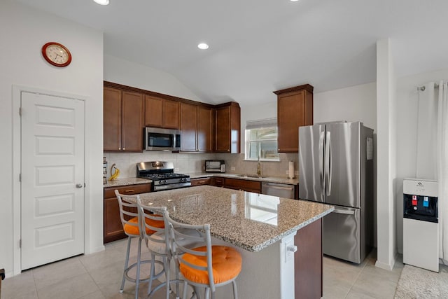 311 Spiny Lizard Ln, San Marcos, TX 78666 - kitchen featuring stainless steel appliances, a sink, light tile patterned floors, a kitchen island, and vaulted ceiling