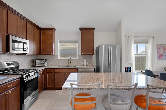 311 Spiny Lizard Ln, San Marcos, TX 78666 - kitchen featuring stainless steel appliances, a sink, a breakfast bar area, backsplash, and a kitchen island