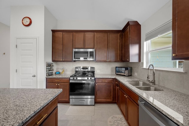 311 Spiny Lizard Ln, San Marcos, TX 78666 - kitchen featuring appliances with stainless steel finishes, a sink, tasteful backsplash, light stone counters, and vaulted ceiling