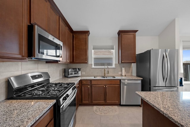 311 Spiny Lizard Ln, San Marcos, TX 78666 - kitchen with stainless steel appliances, a sink, light stone counters, backsplash, and light tile patterned flooring